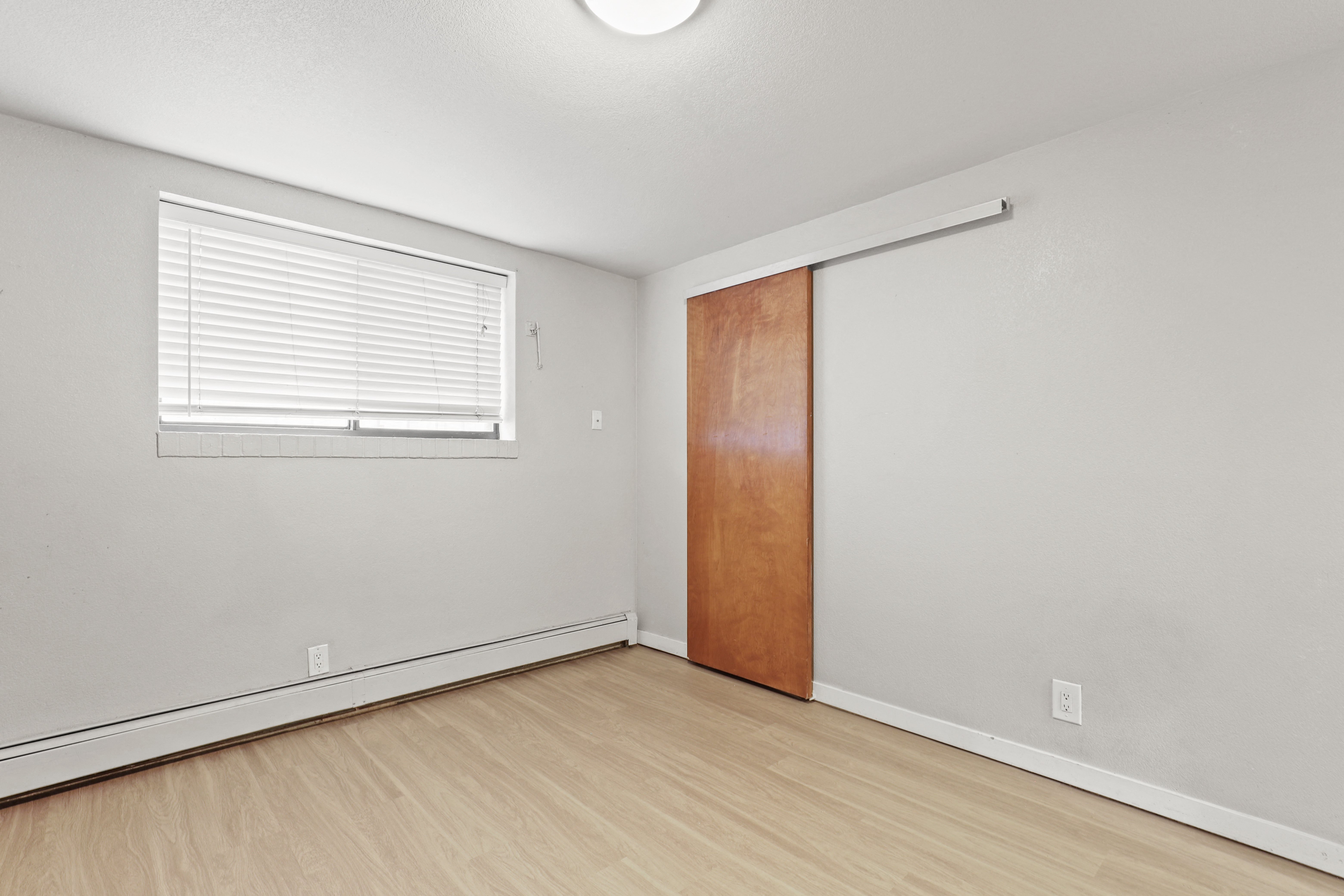 the living room of an apartment with a door and a window